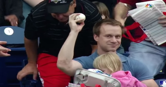Pap&aacute; atrapa pelota de b&eacute;isbol mientras carga a su hija