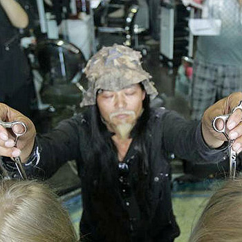Peluquero chino corta el pelo con los ojos cerrados